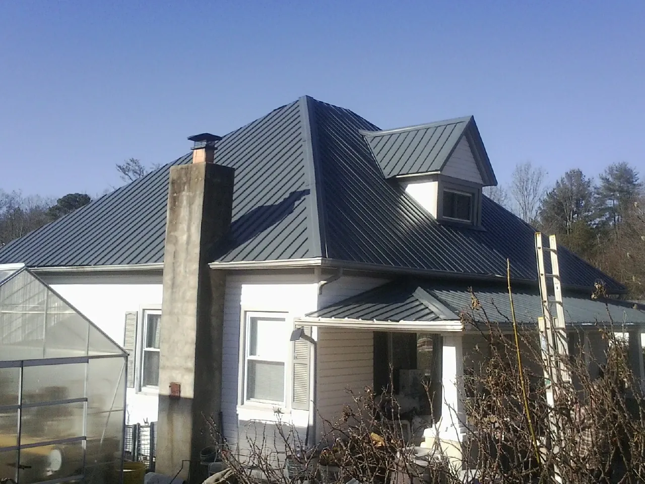 Dark blue standing seam metal roof on a white farmhouse with dormer — Slate & Tile Roof Repair by Roofing Brothers in Kennesaw