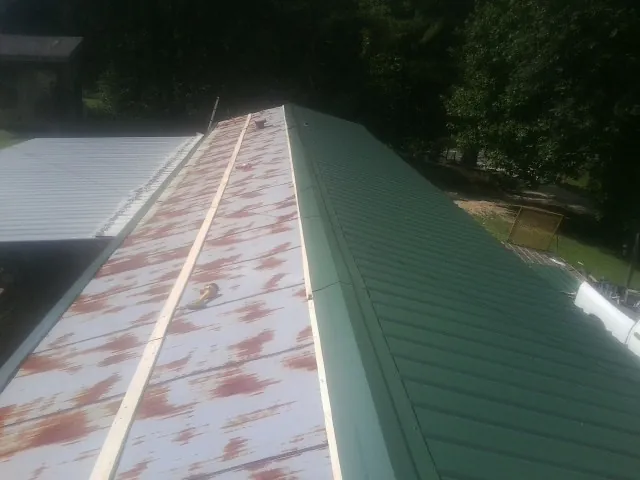Old rusted panels beside newly installed green metal roofing — Wind Damage Roof Repair by Roofing Brothers in Kennesaw