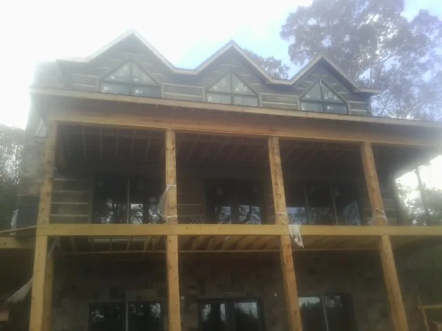 Dormers and porch framing on a large log home under construction — Roof Coating work by our crew in Kennesaw