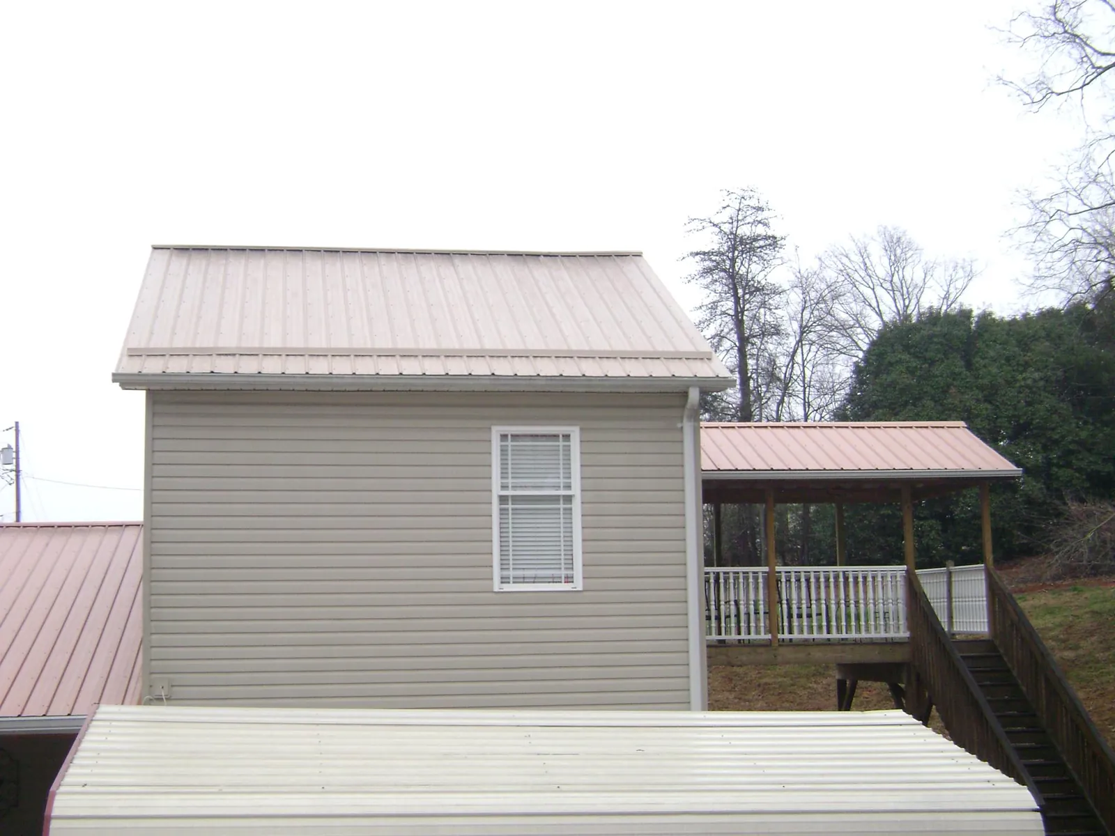 Tan metal roofs on a two story addition and attached porch, from a Roof Replacement job in Kennesaw