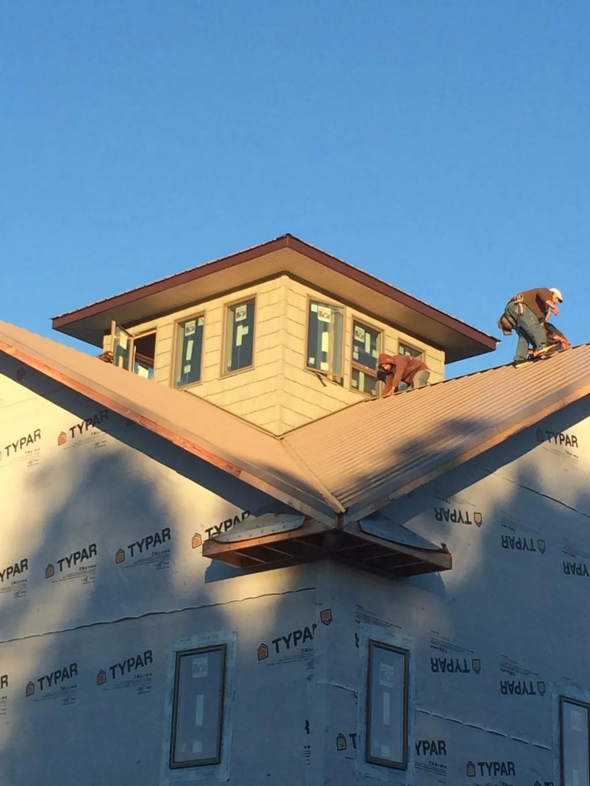 Roofers working around a rooftop cupola on a new metal roof at sunset — Roof Waterproofing in Kennesaw by Roofing Brothers